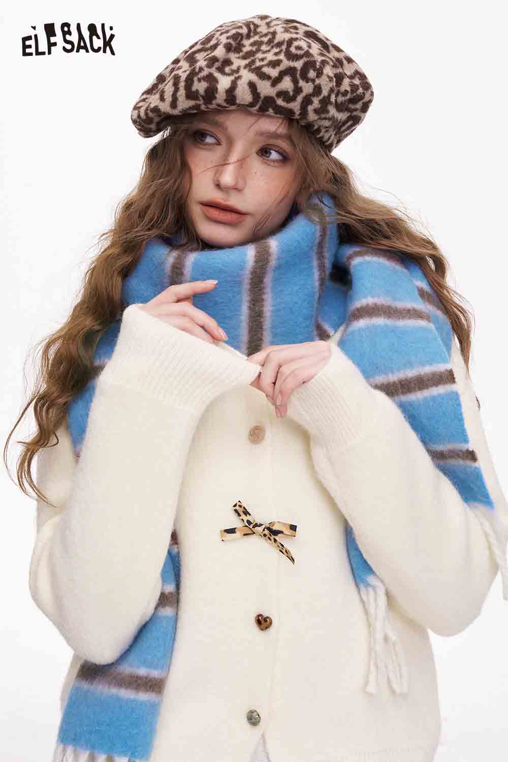 ELFSACK preppy striped fringe scarf in blue and brown worn with a cozy white cardigan