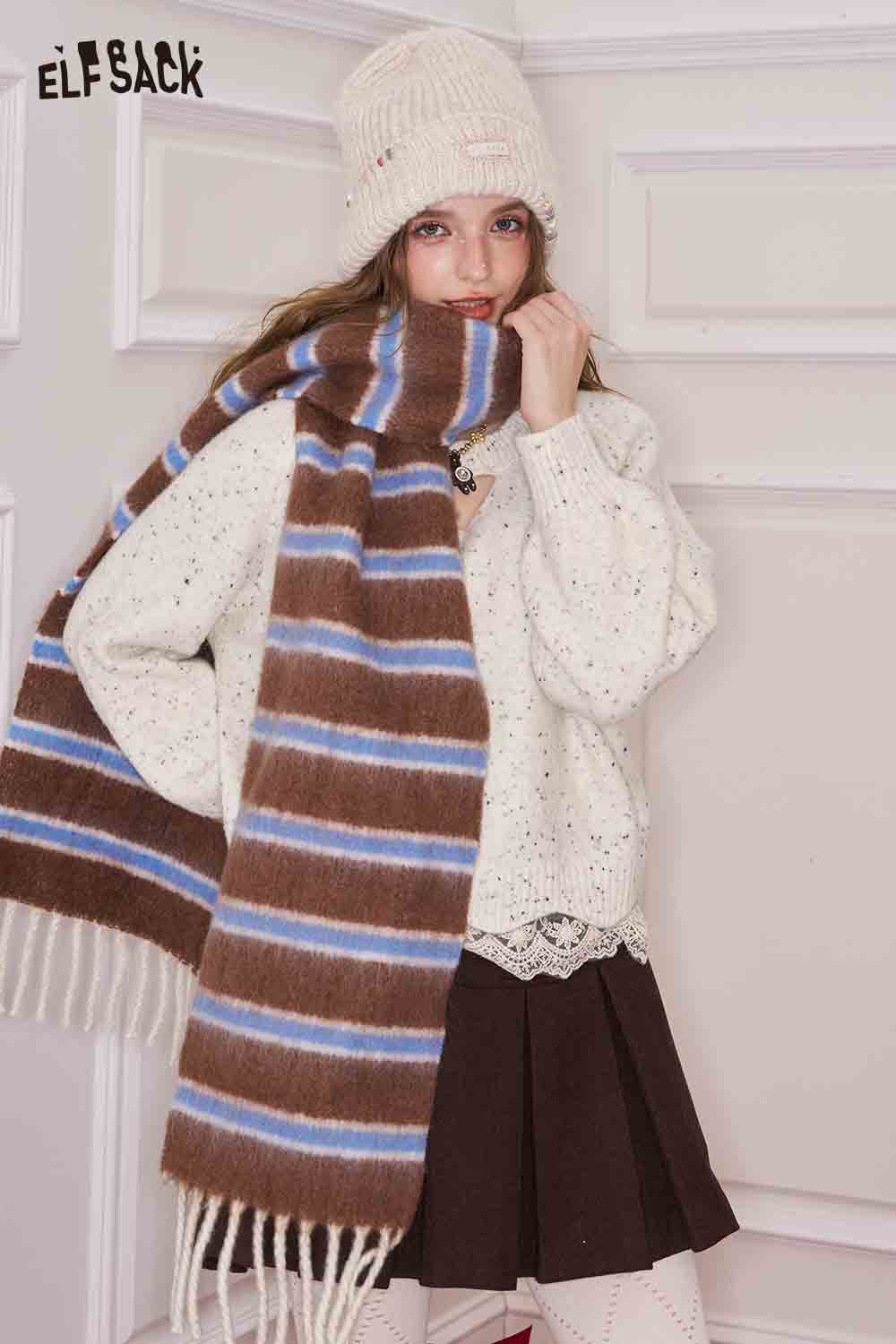 ELFSACK preppy striped fringe scarf in brown and blue, styled with a cozy outfit and a hat for winter fashion