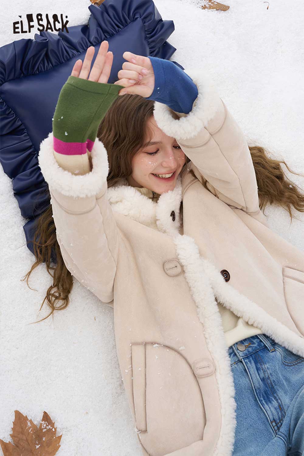 ELFSACK soft contrast sleeve knitwear worn by a girl smiling in the snow, featuring vibrant colored sleeves