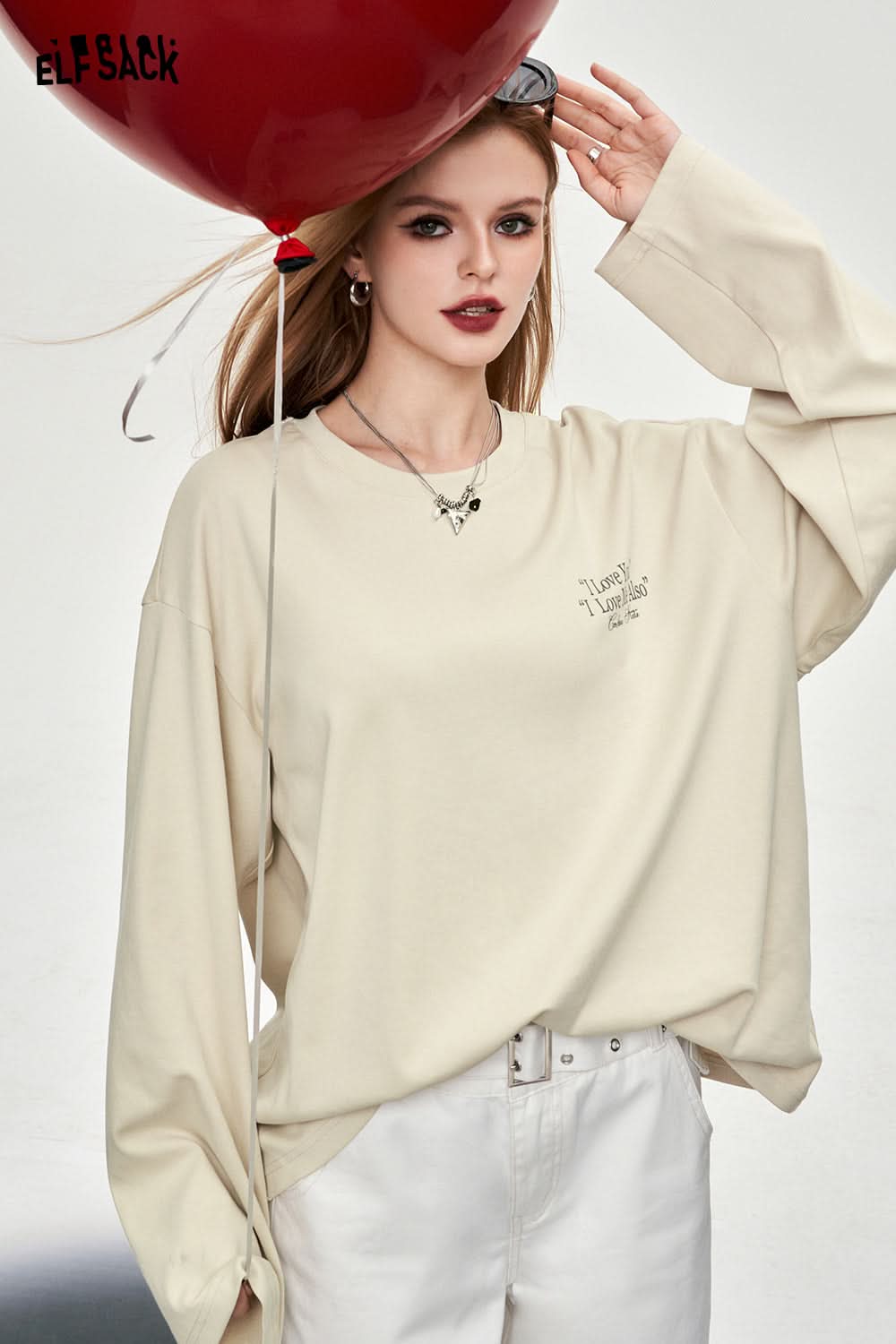 ELFSACK beige oversized T-shirt with Y2K Alphabet Graphic text worn by model holding red balloon