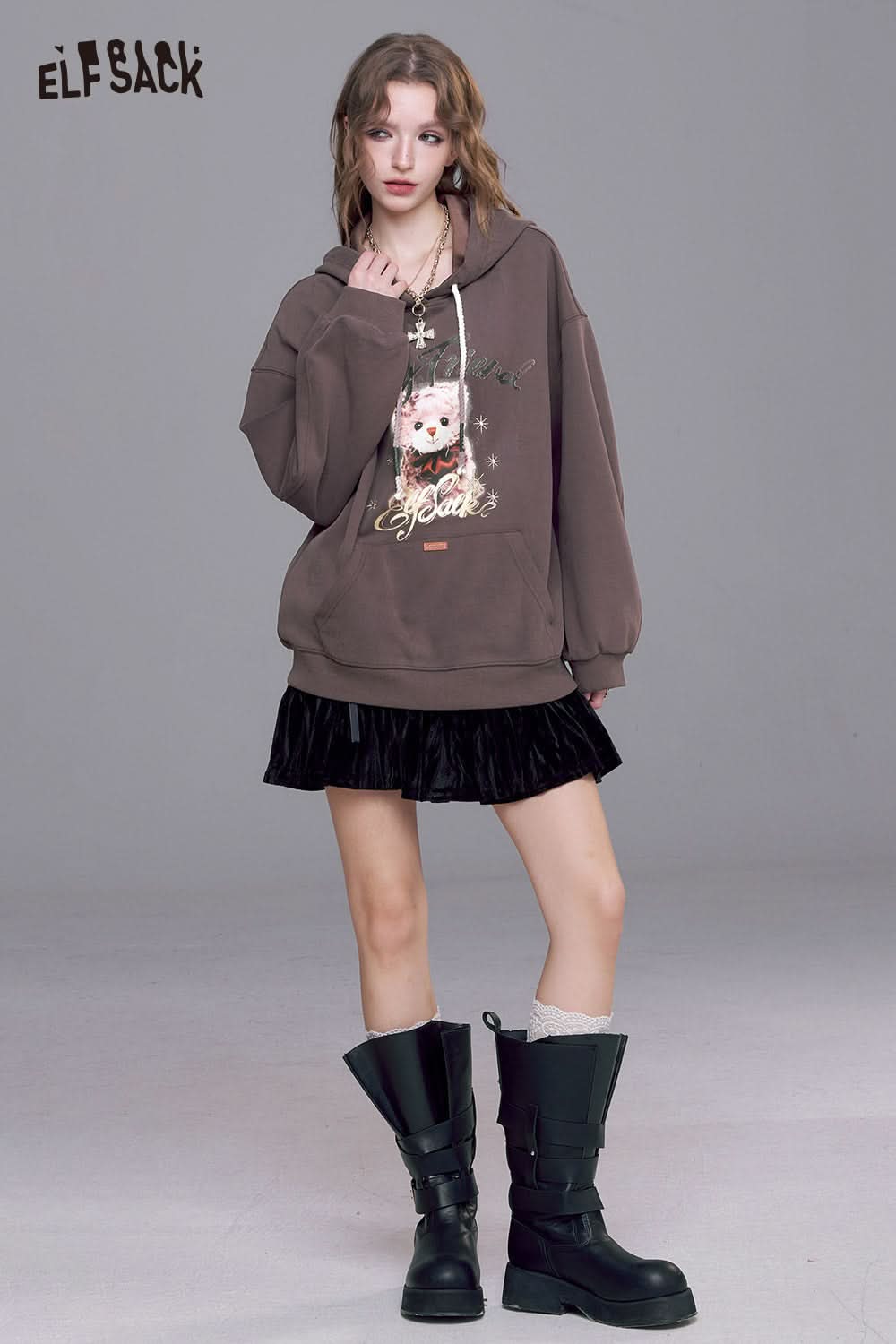 ELFSACK vintage cartoon graphic hoodie in brown with a playful design paired with a black skirt and stylish boots