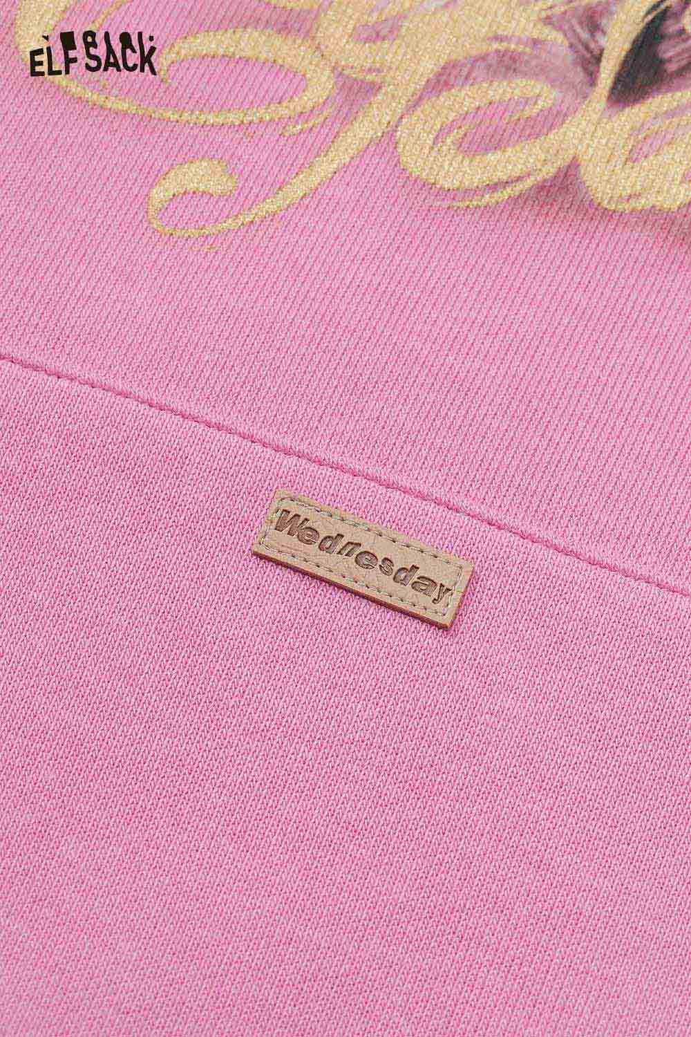 Close-up of ELFSACK vintage cartoon graphic hoodie in pink featuring a unique design and branding tag