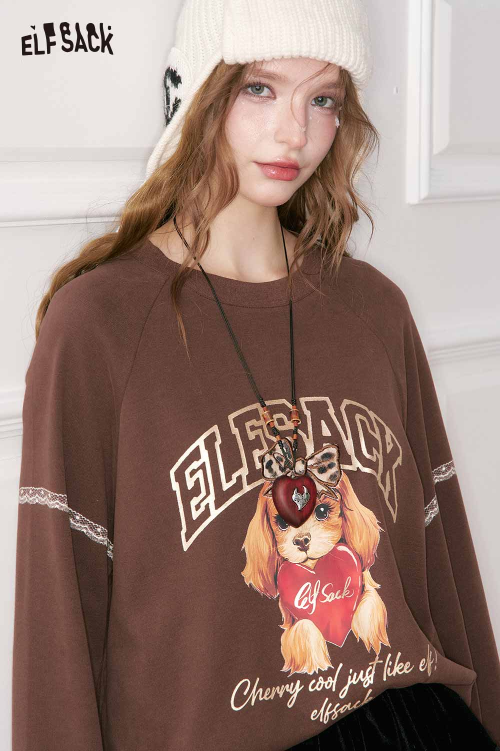 Model wearing ELFSACK vintage heart pendant necklace with a dog graphic sweatshirt and knit beanie