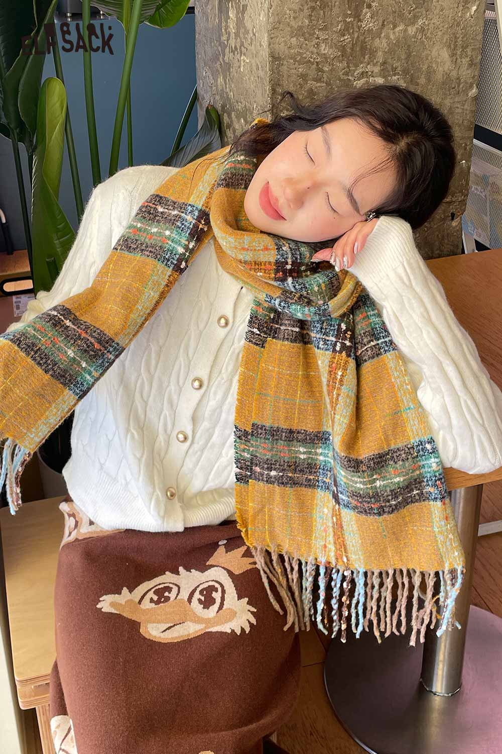 Cozy model wearing a vintage plaid wool scarf in warm colors paired with a cream sweater