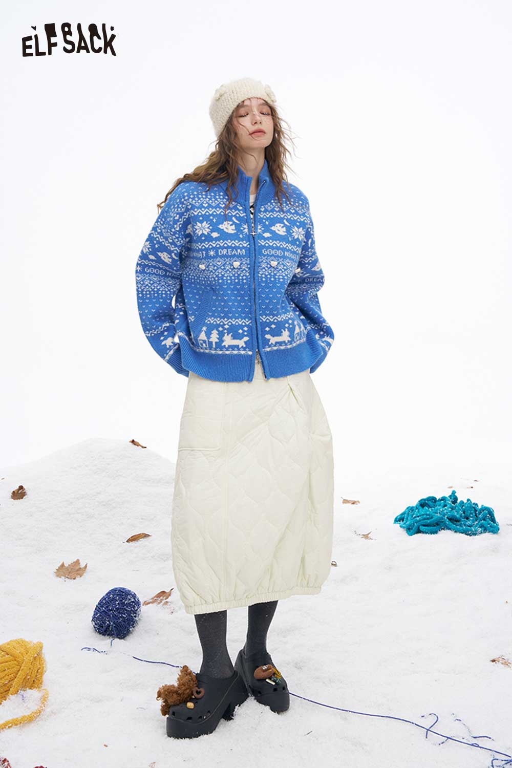 ELFSACK women's down half skirt paired with a blue knitted sweater and winter accessories in a snowy setting