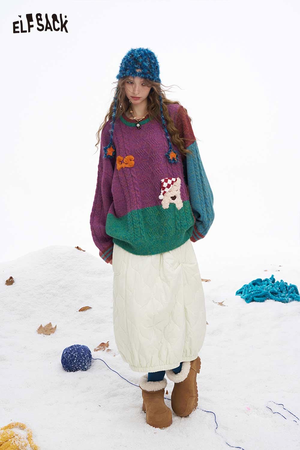 ELFSACK women's down half skirt styled with a colorful knitted sweater and winter accessories in a snowy setting