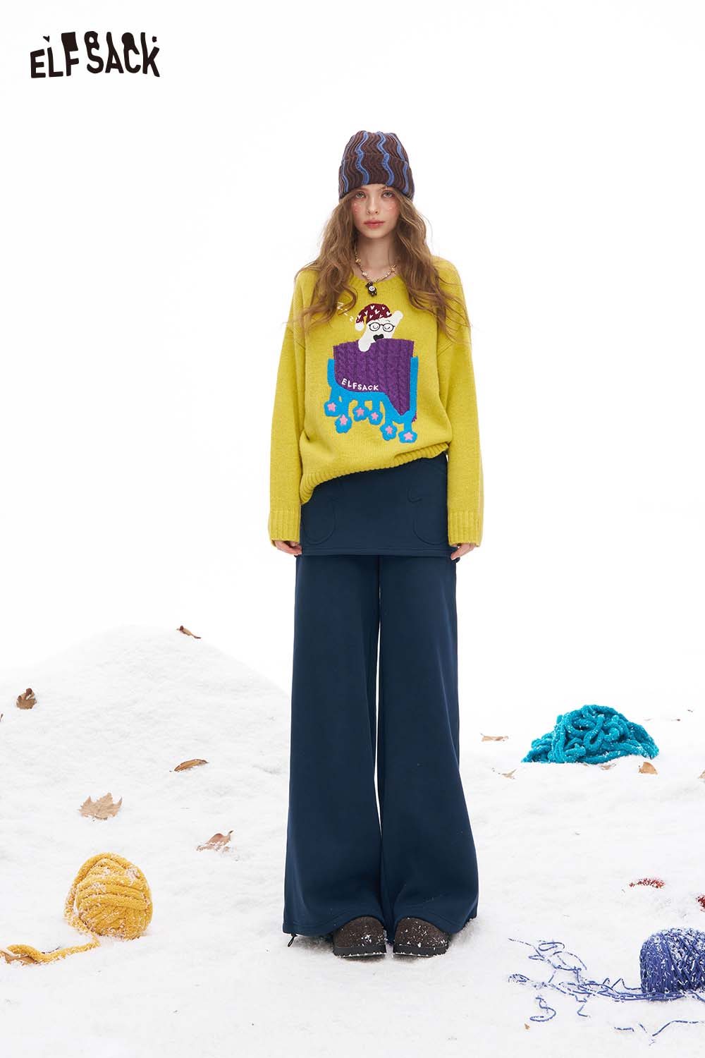 Fashionable women's floor length wide leg pants paired with a colorful sweater and winter hat