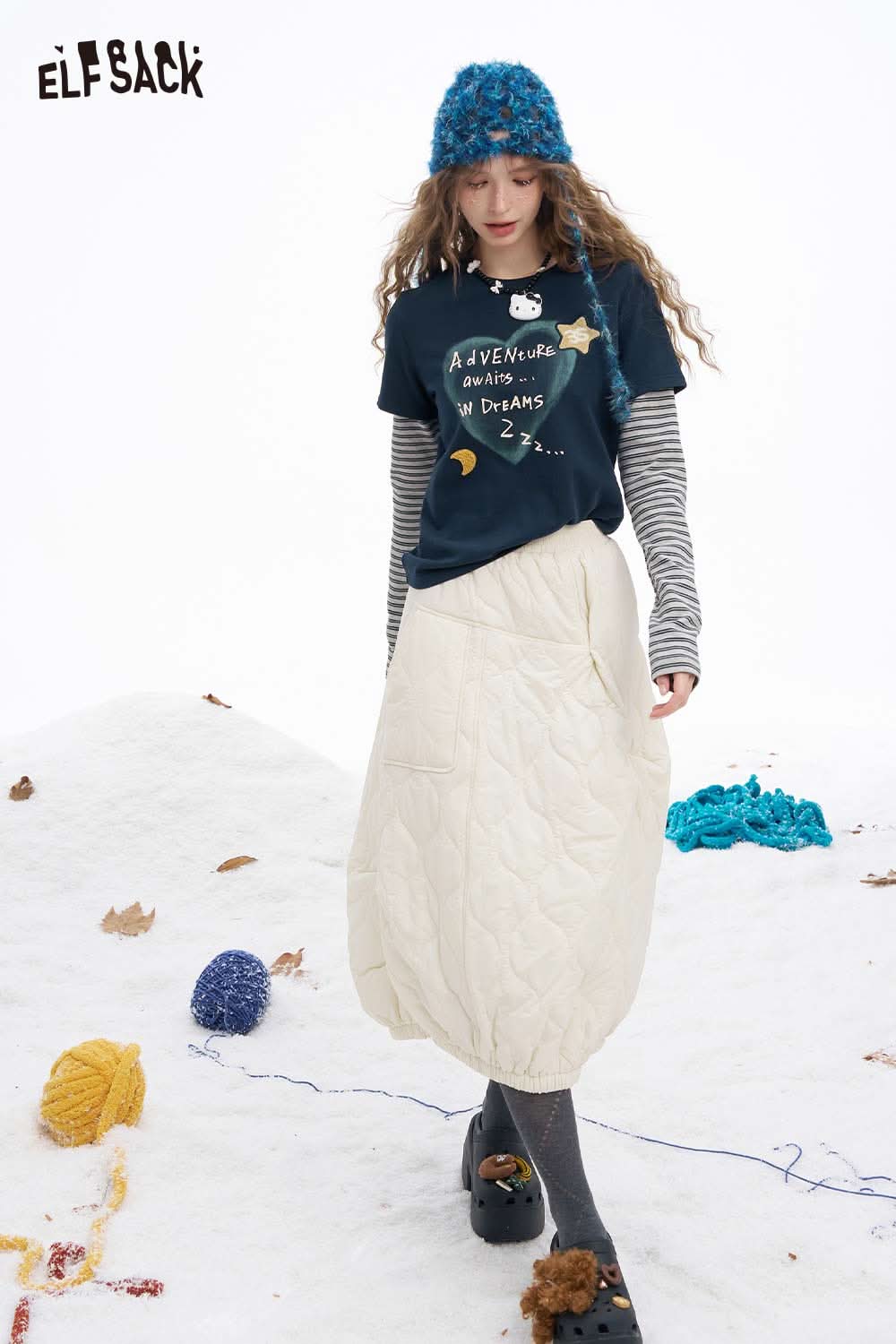 ELFSACK women's graphic embroidered long sleeve tshirt paired with a cozy quilted skirt in a snowy setting