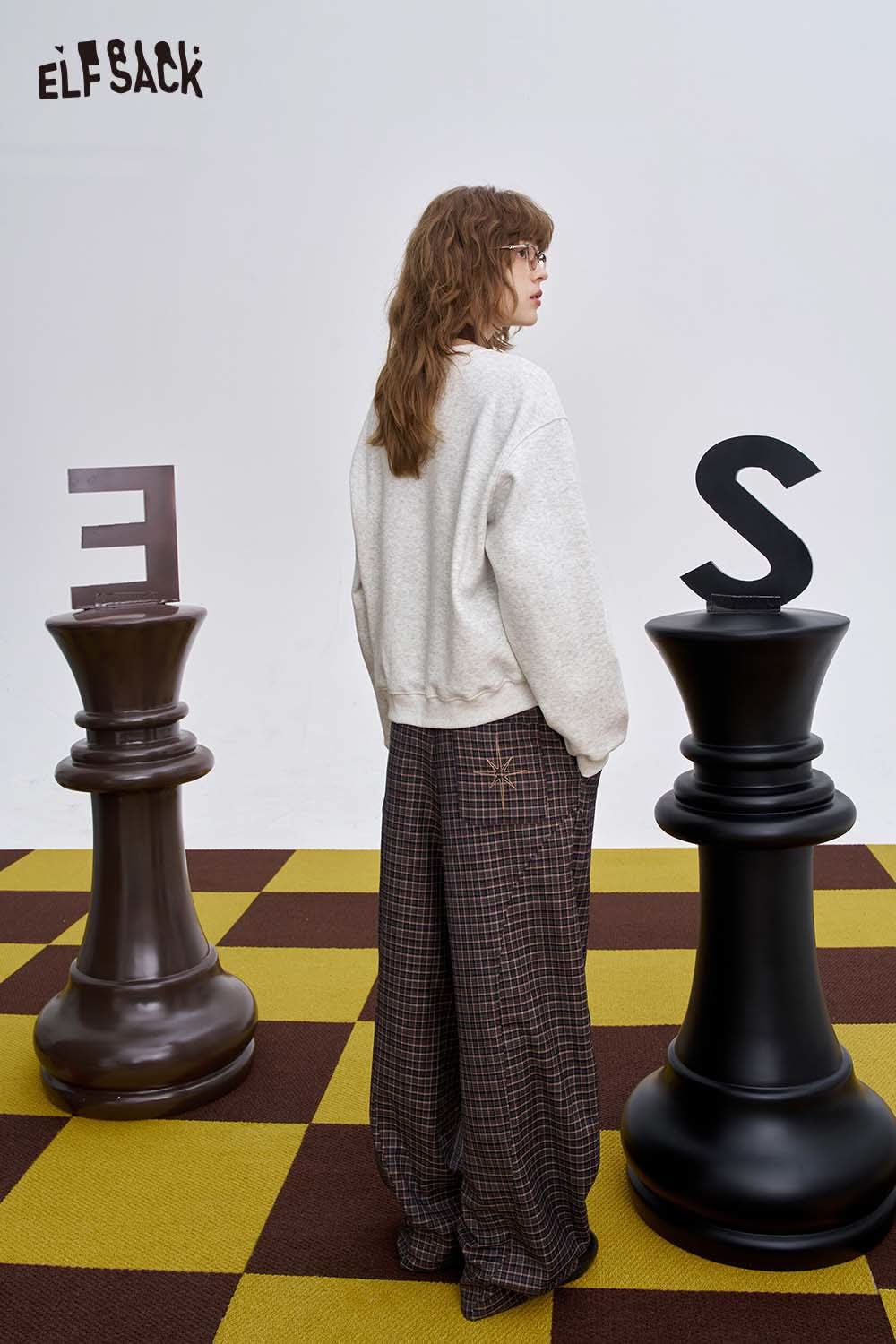 Women's graphic sweatshirt by ELFSACK styled with plaid pants in a unique chessboard setting