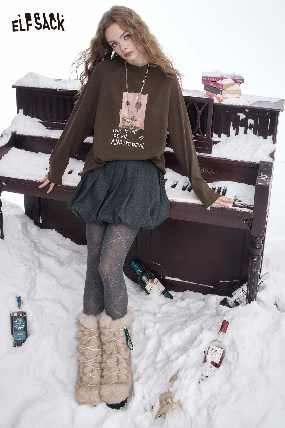 ELFSACK women's letter graphic long sleeve t-shirt in brown paired with skirt and boots, styled in a snowy setting