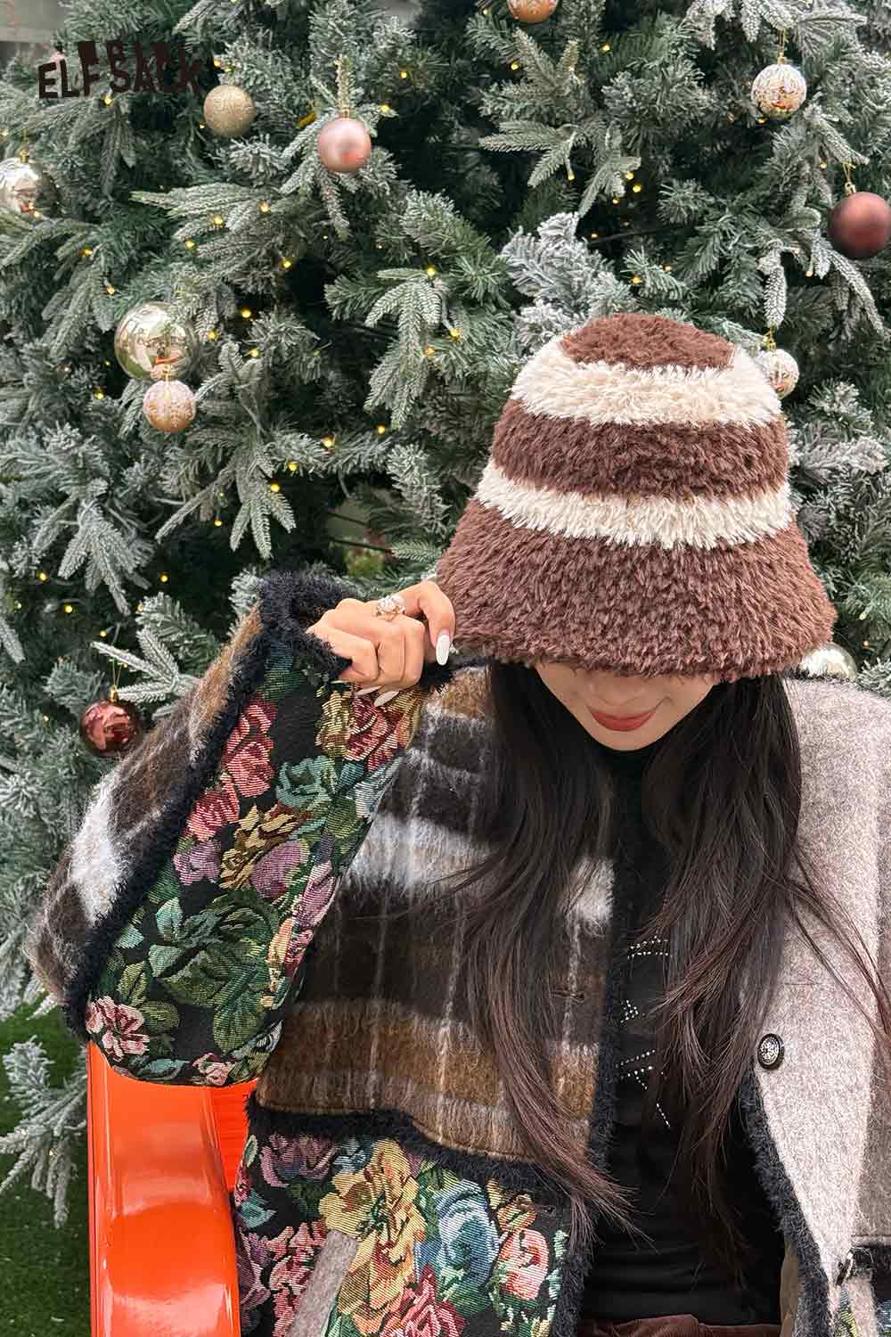ELFSACK women's plush bucket hat in brown and cream stripes worn with a floral jacket outdoors