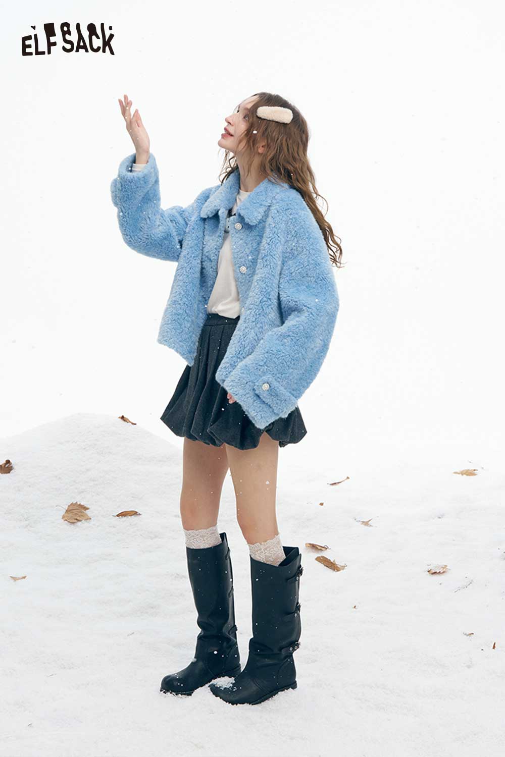 ELFSACK women's plush stand collar coat in blue worn with a skirt and boots, standing in snow
