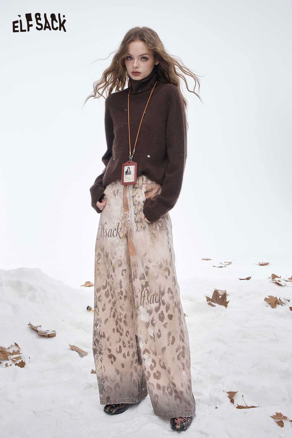 ELFSACK wool high neck sweater women in brown paired with stylish wide-leg pants on a snowy backdrop