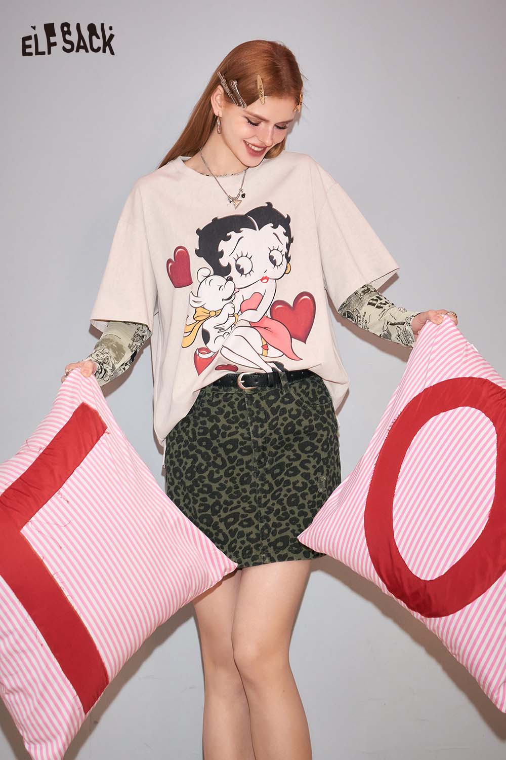 ELFSACK animal print denim mini skirt paired with a graphic tee and holding decorative pillows