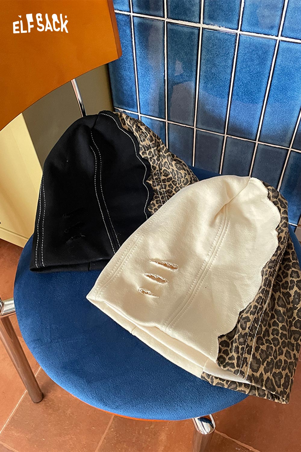 ELFSACK animal print slouchy beanie in black and cream designs displayed on a blue chair