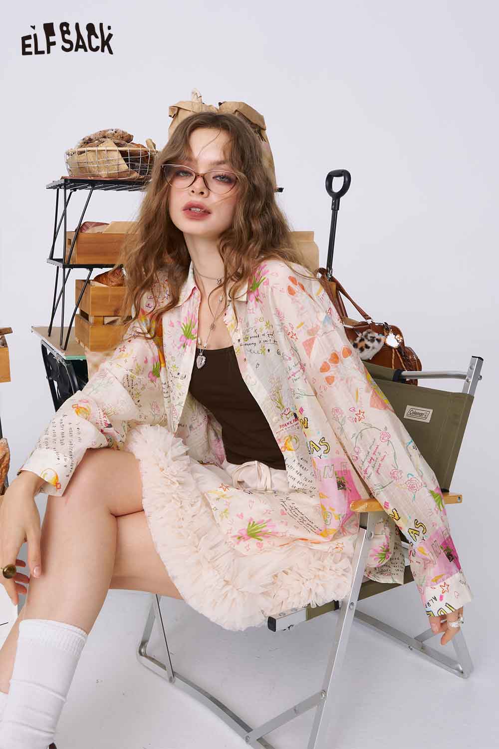 ELFSACK graffiti cartoon print shirt for women styled oversized pastel long sleeve shirt on model seated with ruffle skirt