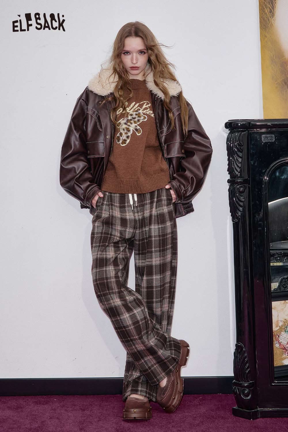 ELFSACK bear embroidery knit top paired with a brown leather jacket and plaid trousers