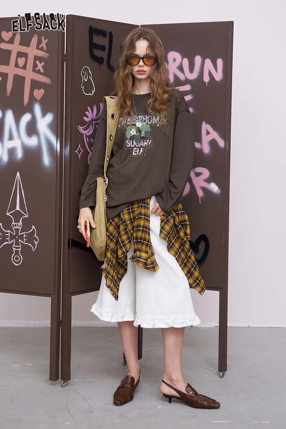 
                  
                    ELFSACK oversized daisy graphic tee for women styled with plaid shirt tied at waist white midi skirt ruffle hem
                  
                
