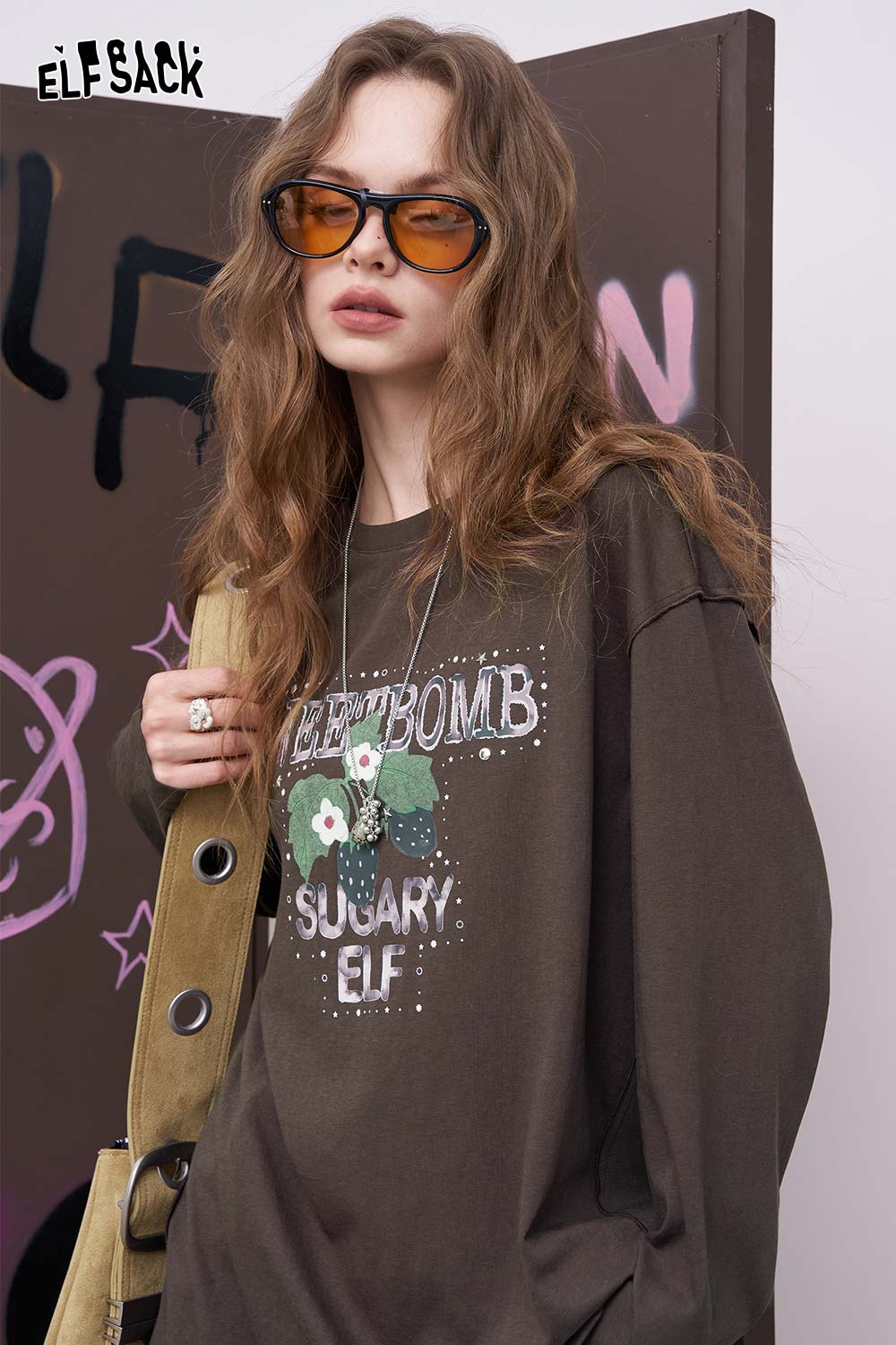 
                  
                    ELFSACK model wearing brown oversized daisy graphic tee for women with vintage floral print and relaxed fit
                  
                