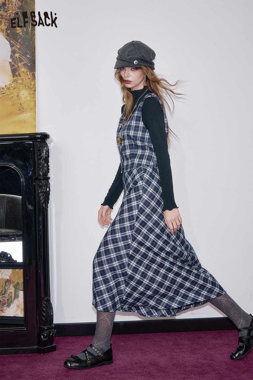 Model wearing a breathable plaid a-line skirt set from ELFSACK with a black long-sleeve top and stylish hat