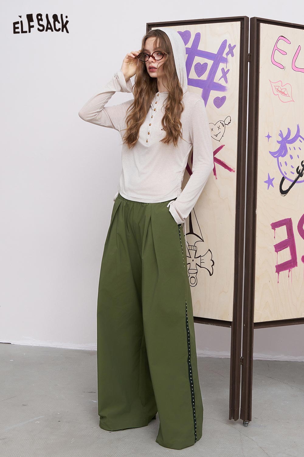ELFSACK model wearing breathable straight leg pants for women in olive green with white hooded top