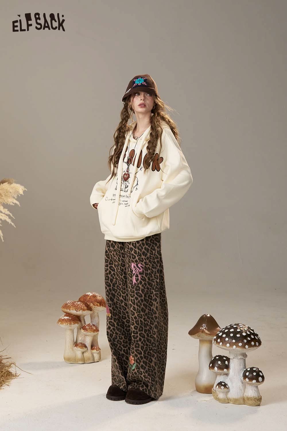 ELFSACK cartoon elephant hooded sweatshirt in cream color, styled with patterned pants for a trendy look