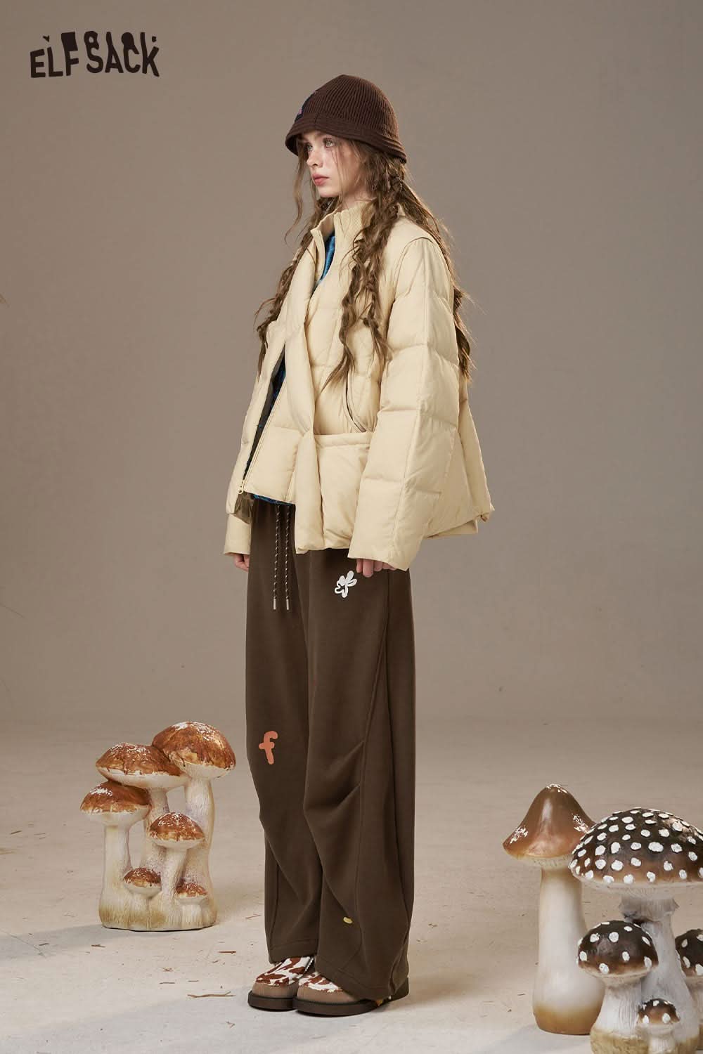 ELFSACK cartoon embroidery sweatpants for women in brown paired with a beige puffer jacket