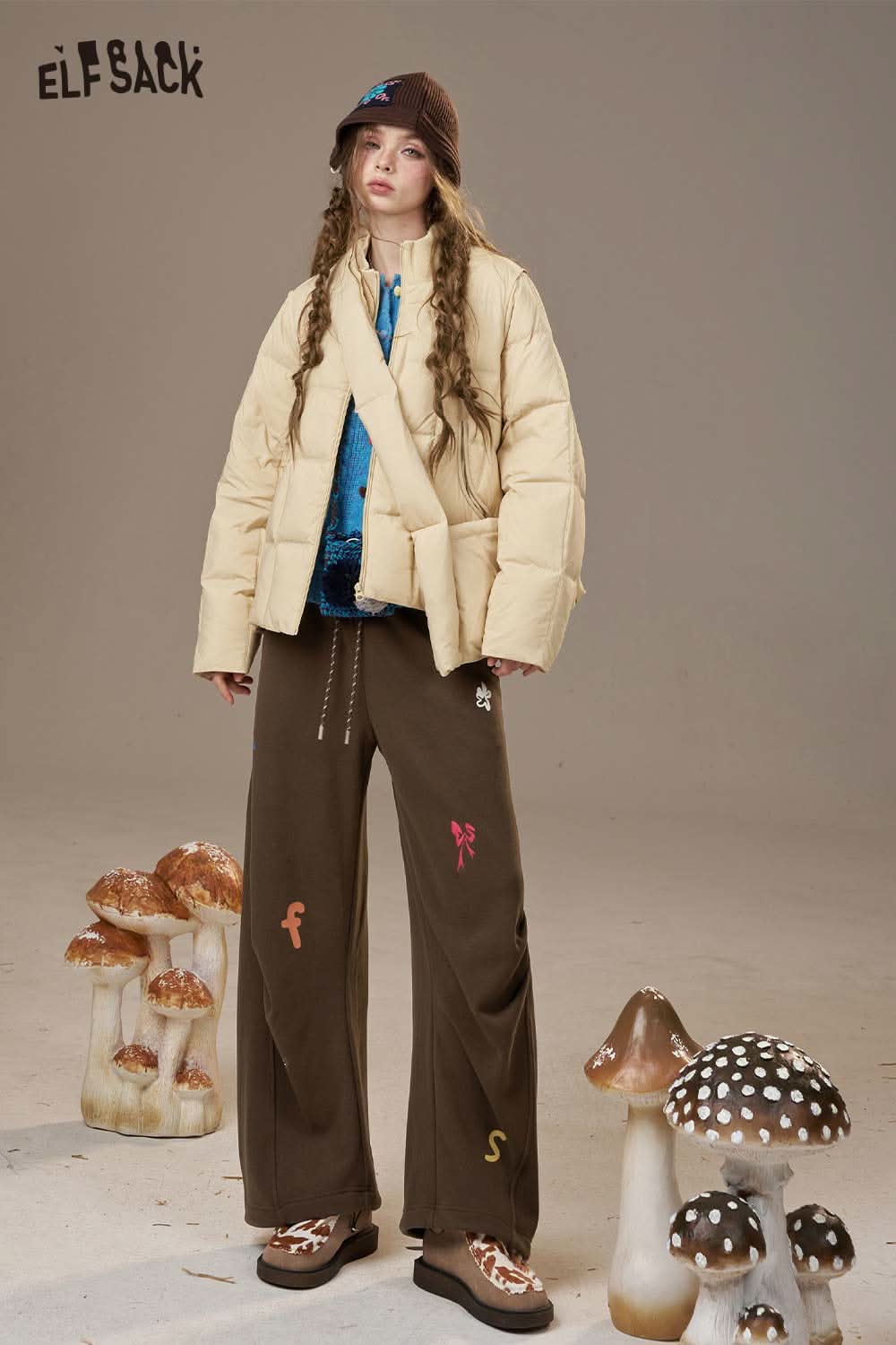 ELFSACK cartoon embroidery sweatpants for women styled with a puffer jacket and accessories in a unique setting