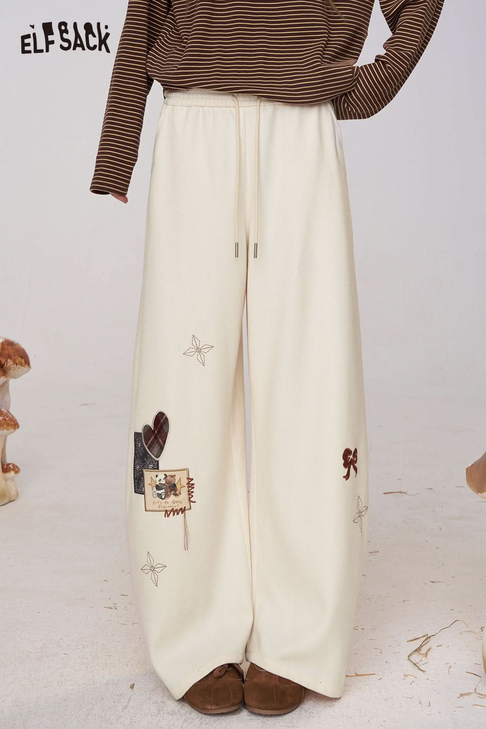 ELFSACK cream cartoon embroidery sweatpants for women with a relaxed fit and unique designs