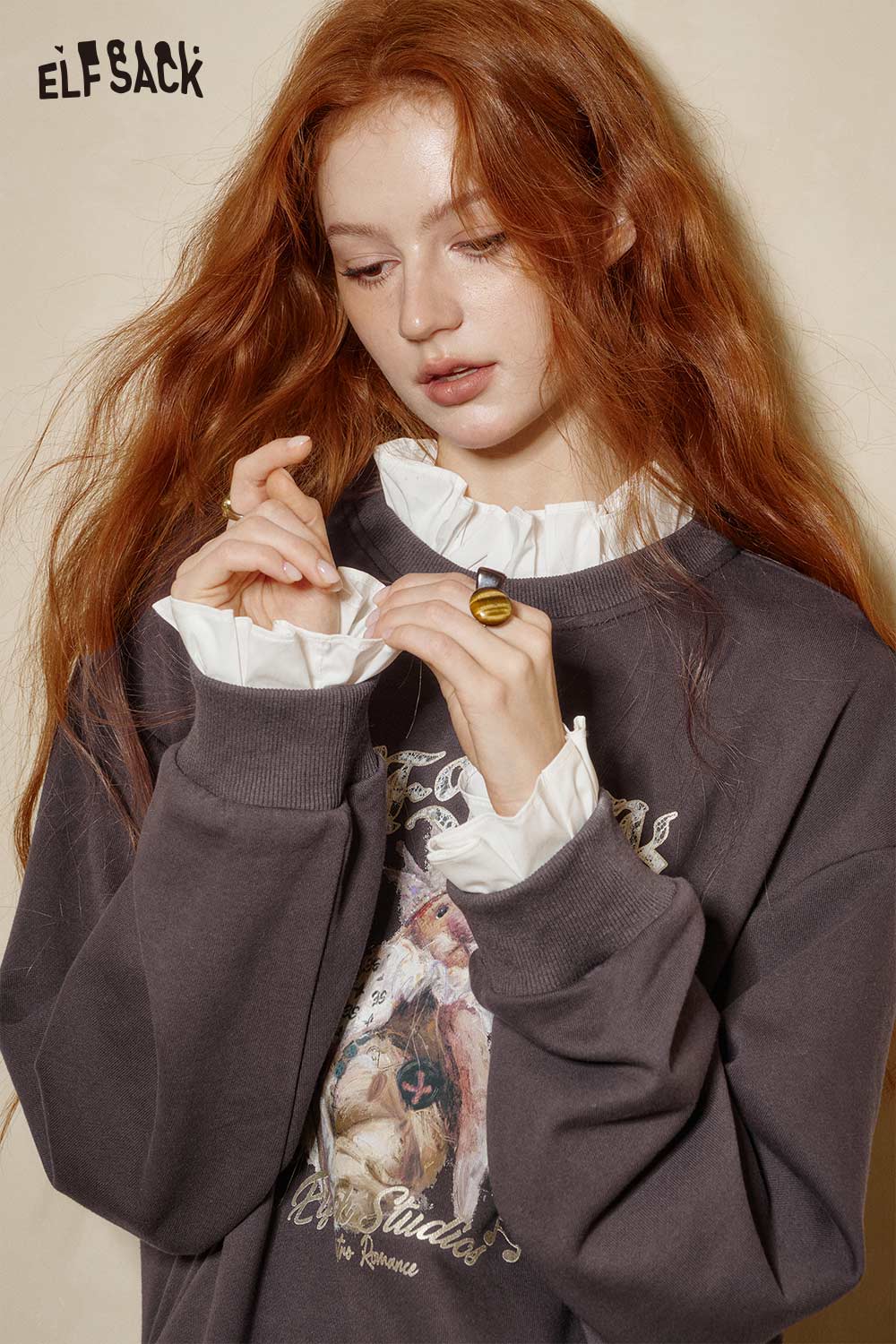 Model wearing a stylish cartoon graphic ruffle sweatshirt by ELFSACK with unique detailing