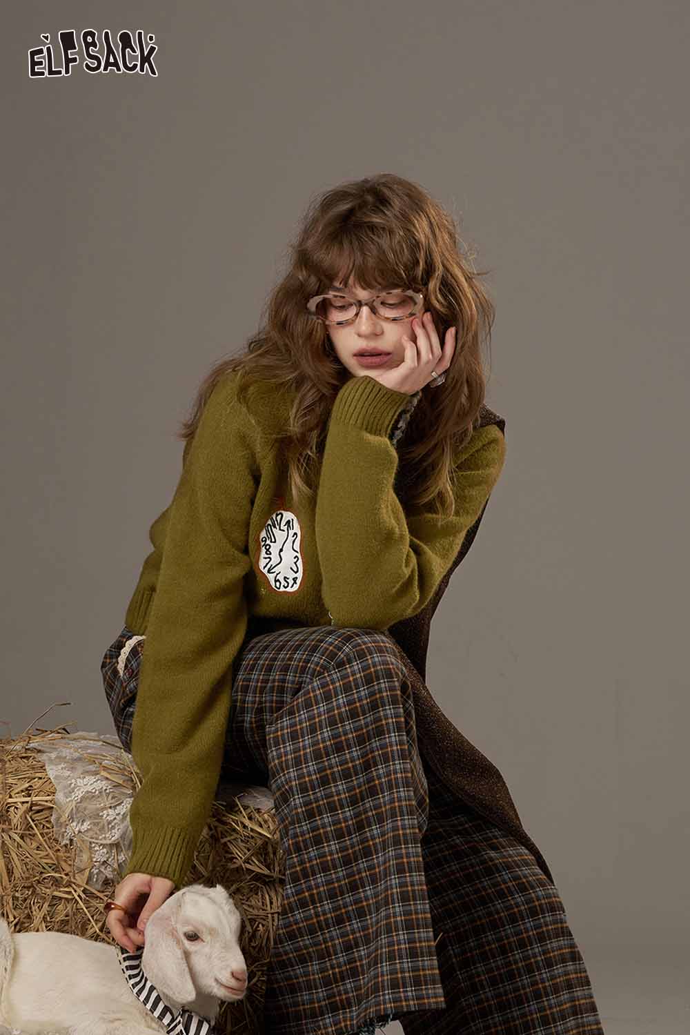 ELFSACK cartoon sweater cardigan for women in olive green, styled with plaid pants and a goat