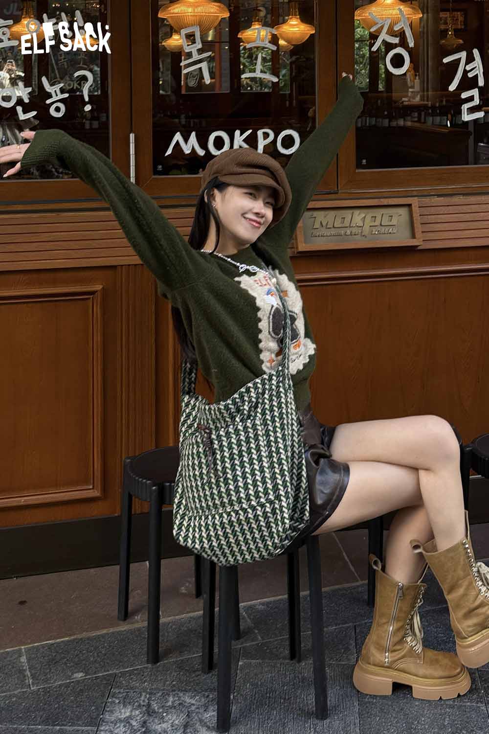 Fashionable model wearing a green sweater with a casual striped crossbody bag for a chic look