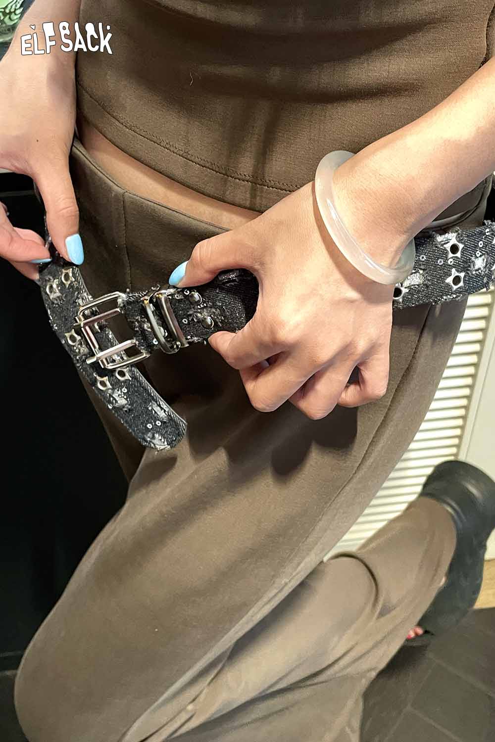 Close-up of a woman adjusting a celestial motif leather belt for women with a unique design and silver buckles