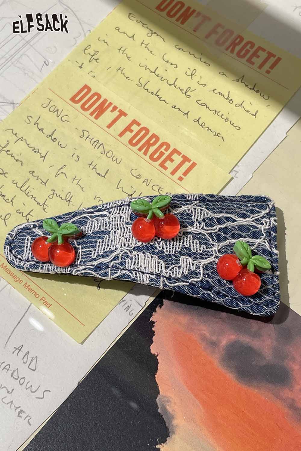 ELFSACK cherry motif hair clip with vibrant cherry design on a denim background