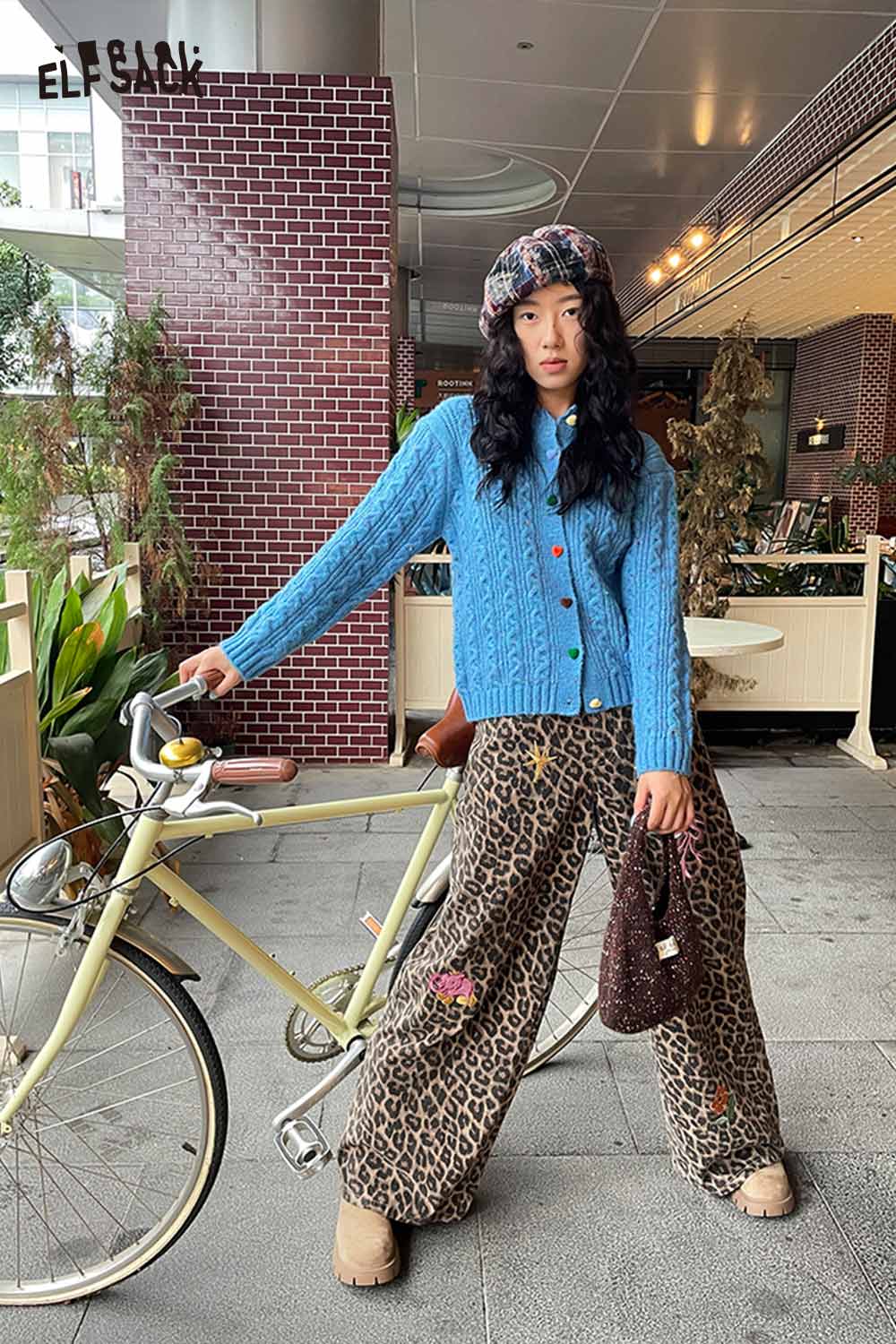 Model wearing a color blocked knitted beret paired with a blue sweater and stylish leopard print pants