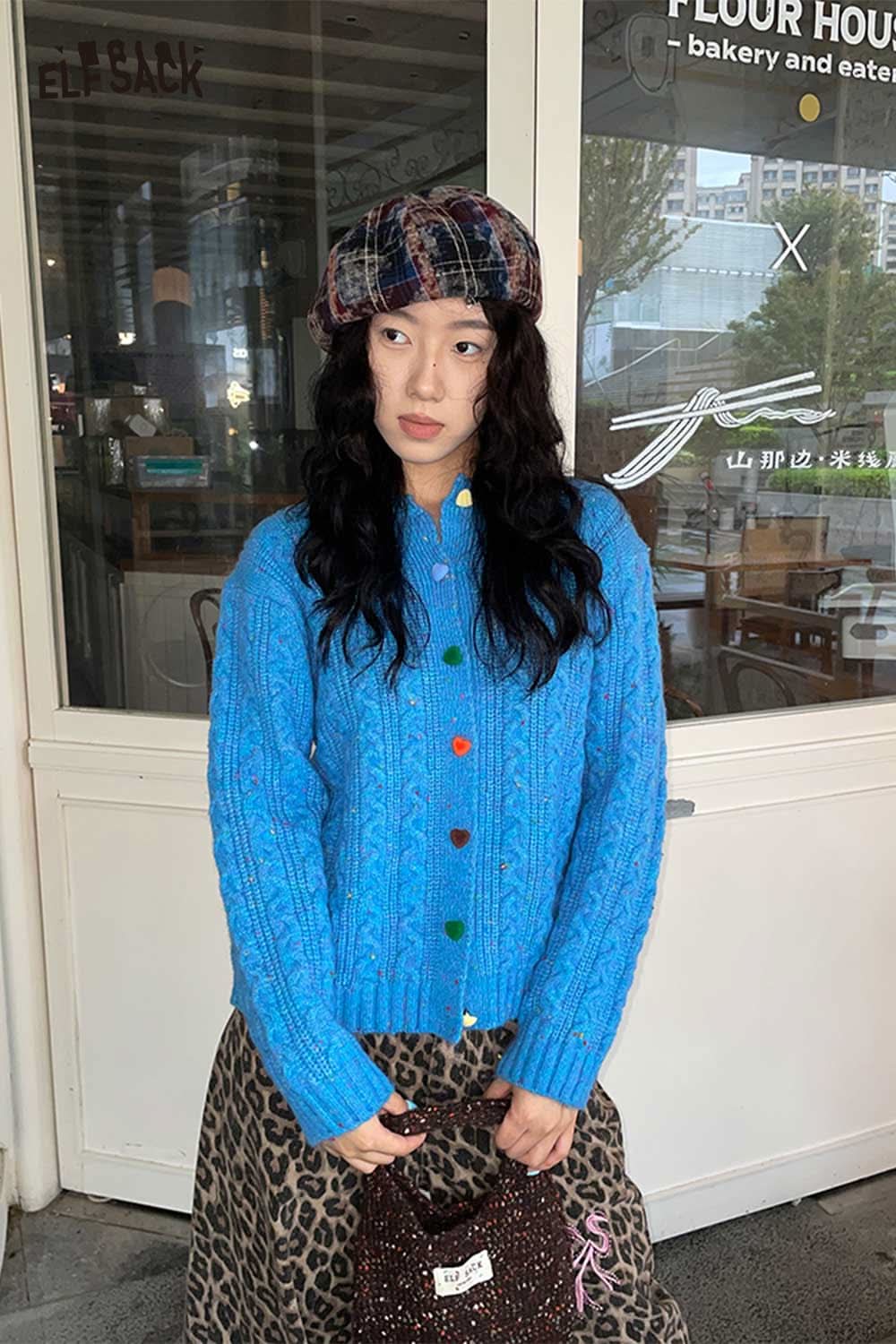 Model wearing a colorful outfit featuring a color blocked knitted beret and a vibrant blue sweater