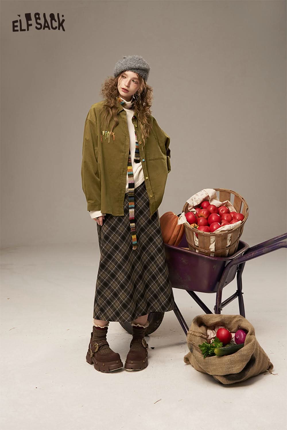 Fashionable model wearing a colorful button pocket shirt for women with a long plaid skirt and boots