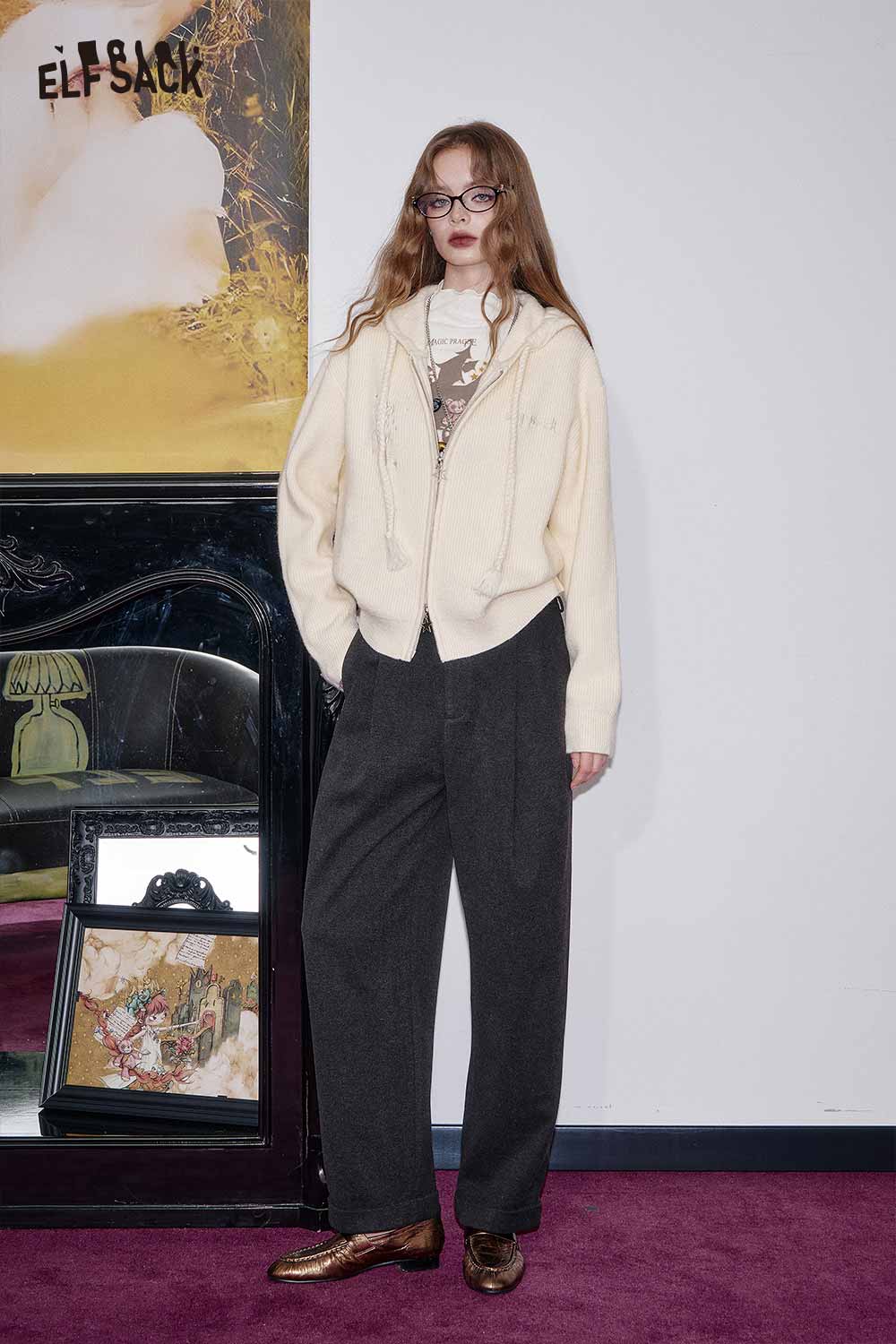 Model wearing a cozy cotton blend embroidered zip up sweater in cream with relaxed-fit trousers