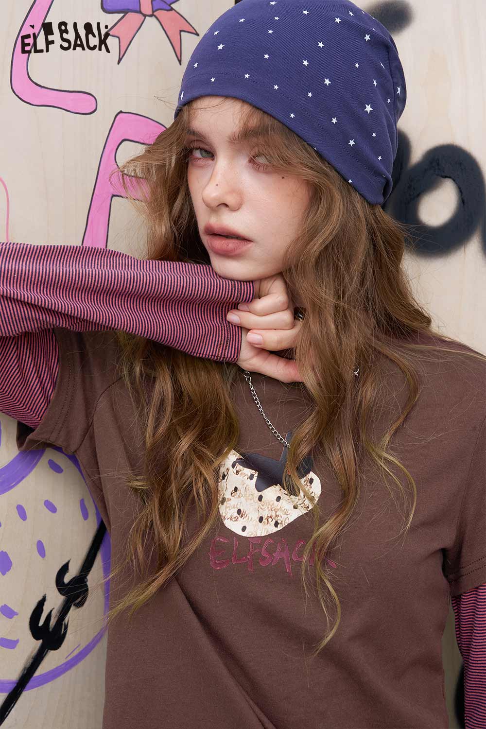 ELFSACK model wearing women's fruit print cotton tee layered over striped sleeves with navy star beanie