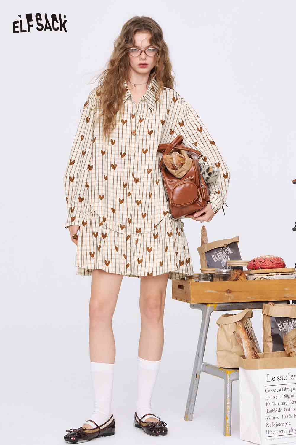 ELFSACK model wearing a college style heart plaid dress cream ruffle hem long sleeves with backpack