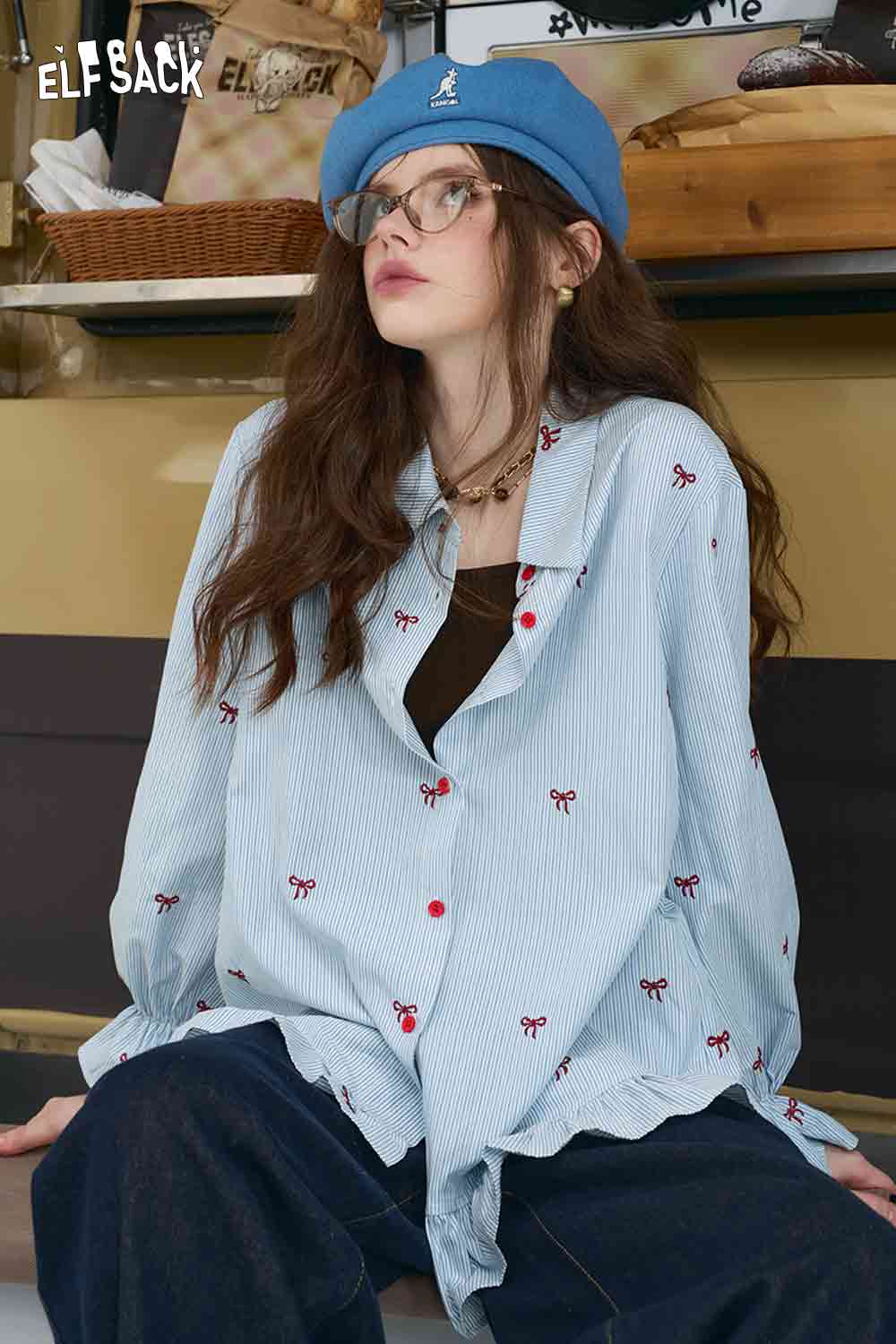 ELFSACK model wearing light blue bow embroidered striped shirt for women with red bow details and ruffle hem