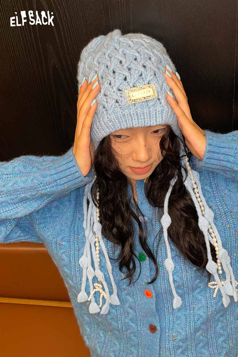 Light blue crocheted tassel ear-flap hat by ELFSACK with long tassels and cozy design