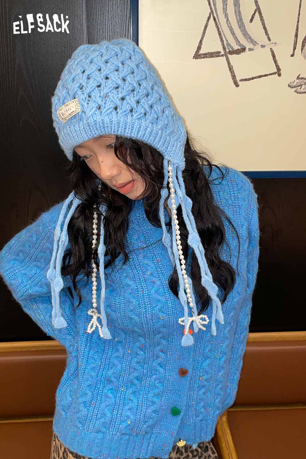 Blue crocheted tassel ear-flap hat from ELFSACK styled with a cozy sweater for a chic look