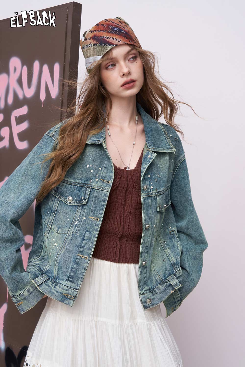 ELFSACK model wearing women's diamond embellished denim jacket over a burgundy knit top and white tiered skirt