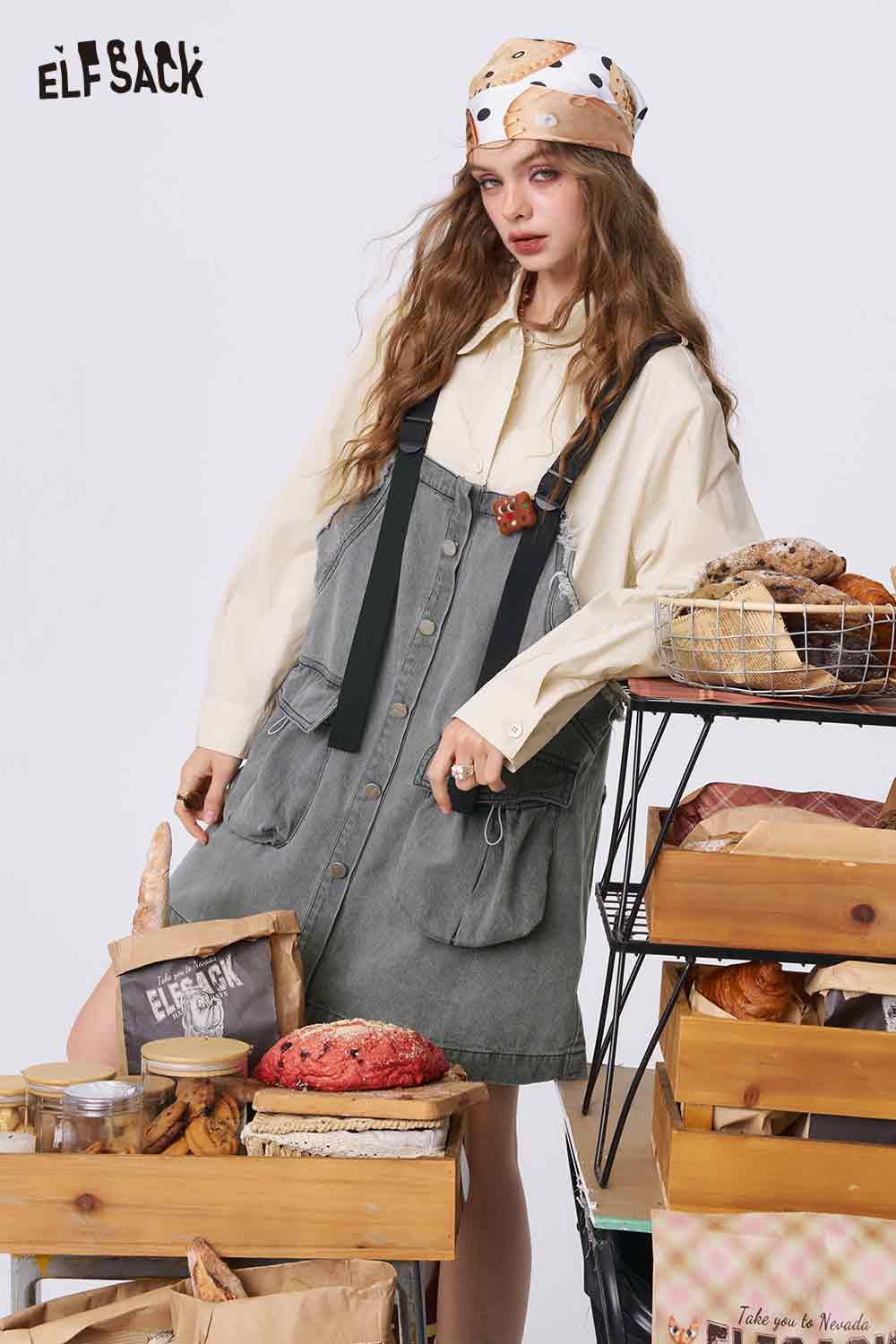 ELFSACK model wearing denim color-block midi dress with button front straps over cream blouse styled with headscarf