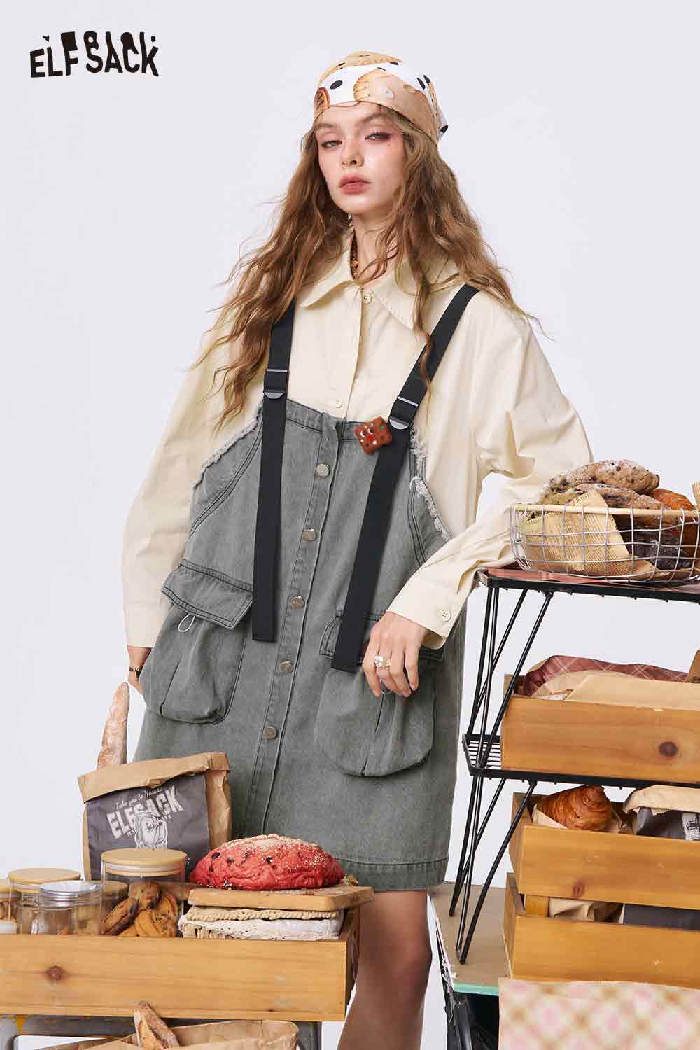 ELFSACK model wearing denim color-block midi dress with utility pockets and black straps over cream blouse