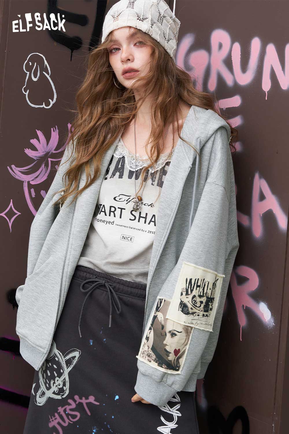 ELFSACK model wearing oversized gray distressed zip up hoodie for women with sleeve patch and beanie