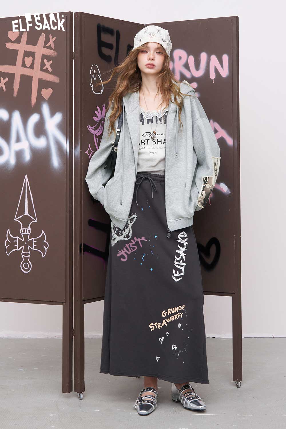 ELFSACK oversized gray distressed zip up hoodie for women styled with graphic tee long graffiti skirt and bandana