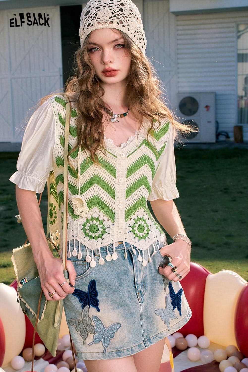 ELFSACK dopamine cardigan in green and white with crochet details and tassels, styled with a denim skirt