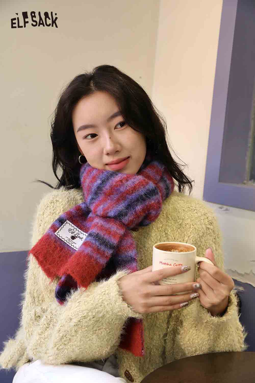Cozy woman wearing a soft Christmas striped scarf for women while holding a cup of coffee